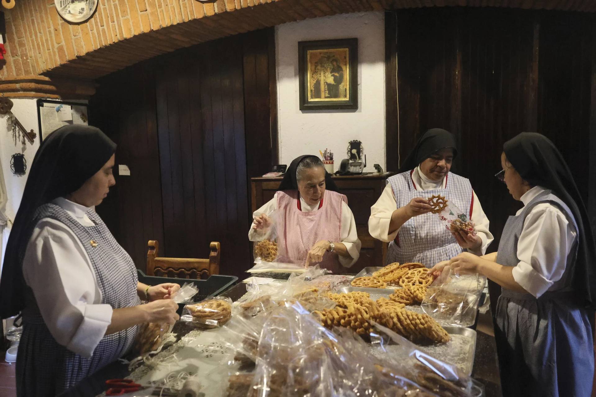 From left, nuns Alejandra Jaime, 39, Maria Ines Maldonado, 76, Maria Auxiliadora Estrada, 59, and Patricia Marin, 28, store fritters with Christmas figures in clear plastic bags for sale at the Convent of the Mothers Perpetual Adorers of the Blessed Sacrament in Mexico City, Thursday, Dec. 7, 2023. (Credit: Ginnette Riquelme/AP.)